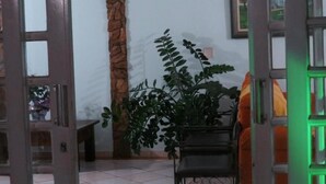 A room with a tiled floor, a bench, a potted plant, and a chair. - La Villa Hotel (Cordeirópolis)