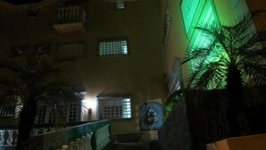 A staircase leading to a building with a green-lit wall and a decorative wall piece. - La Villa Hotel (Cordeirópolis)