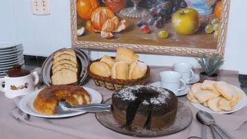 Un buffet per la colazione con diversi dolci, una torta e uno sfondo decorato con frutta.