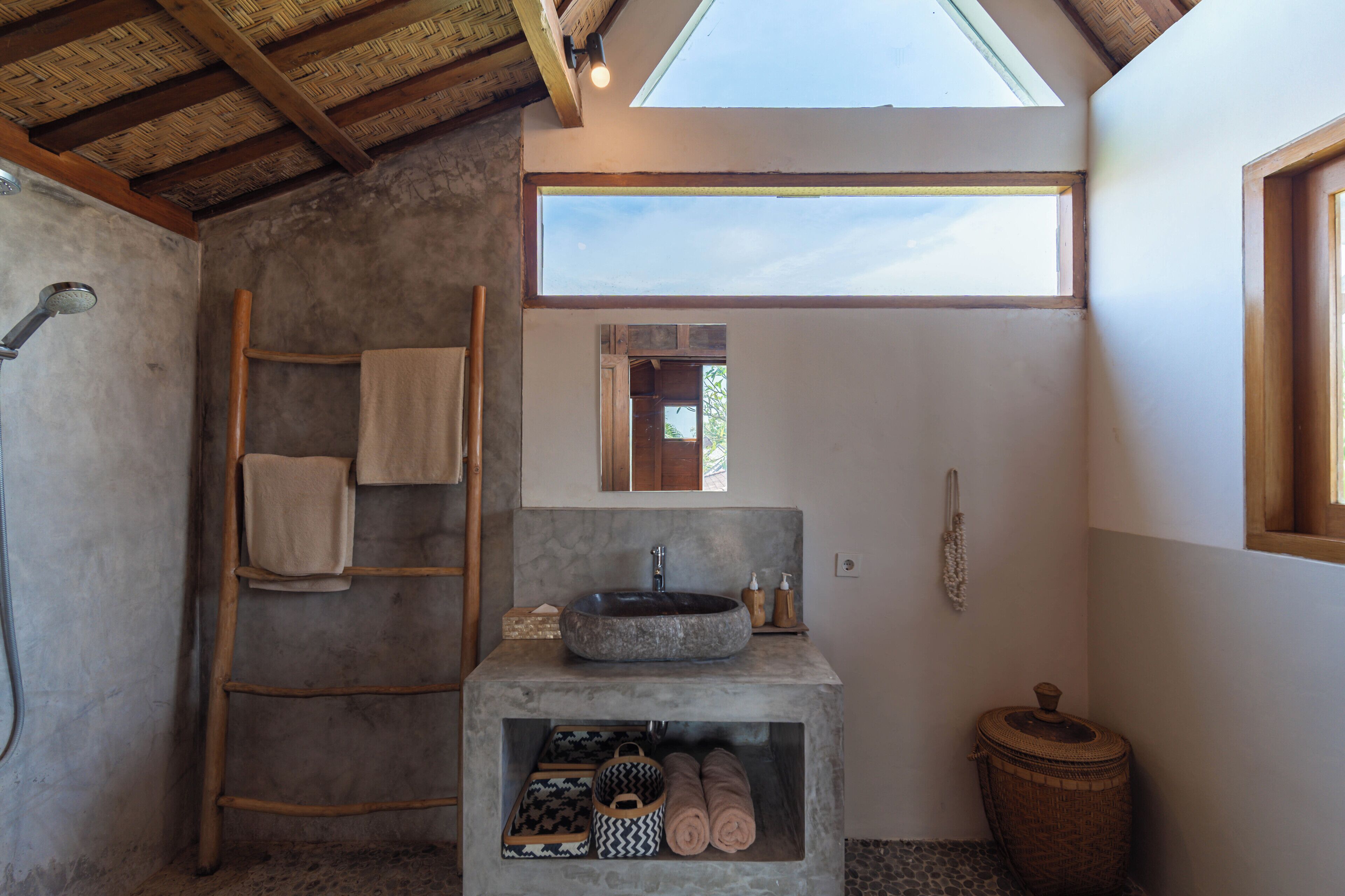 Een badkamer met een stenen wastafel, een houten ladder en een dakvenster.