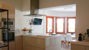 A modern kitchen with built-in appliances, a central island, and a dining area with a view.