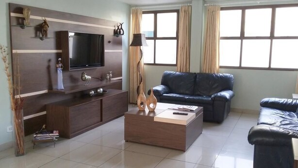Ein modernes Wohnzimmer mit Flachbildfernseher, Couchtisch aus Holz und zwei Sofas.