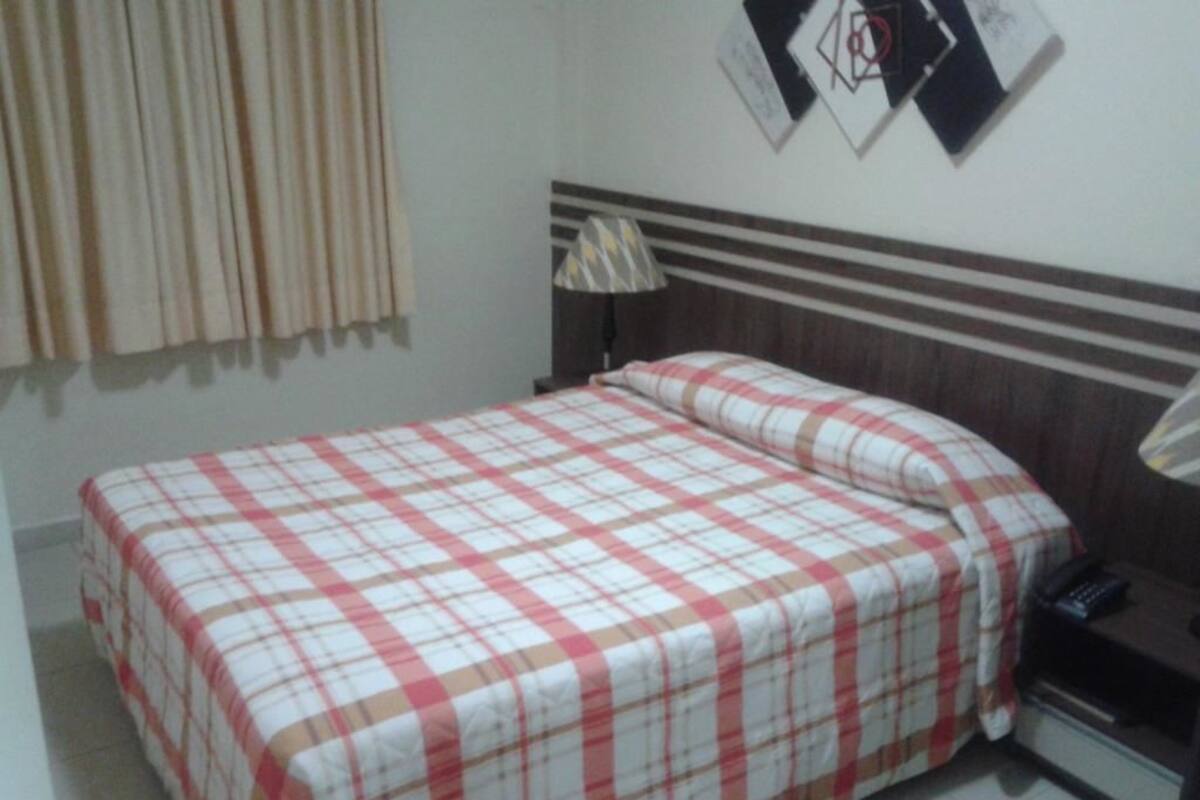 Ein Schlafzimmer mit Bett, Nachttisch, Lampe und Telefon.