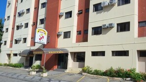Ein mehrstöckiges Hotel mit roter und beiger Fassade, Klimaanlagen und einem Schild, das es als ein Parkhotel kennzeichnet.