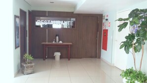 Eine saubere, moderne Lobby mit einem Holzbüro, einem Mülleimer und einem Topfpflanzen.