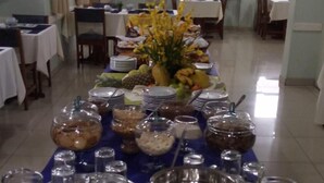 Ein reichhaltiges Buffet mit verschiedenen Speisen und Getränken, einem Blumenschmuck und einem Essbereich mit Tischen und Stühlen.