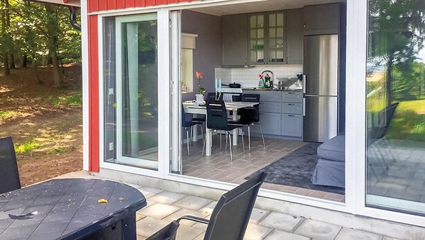 A modern kitchen with a dining area, large sliding glass doors, and a patio with a table and chairs. - 2 bedroom awesome home in Kvidinge (Kvidinge)