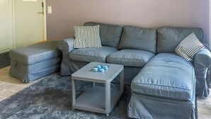 A grey sectional sofa with matching cushions, a grey ottoman, and a small grey table with blue candle-like objects. - 2 bedroom awesome home in Kvidinge (Kvidinge)