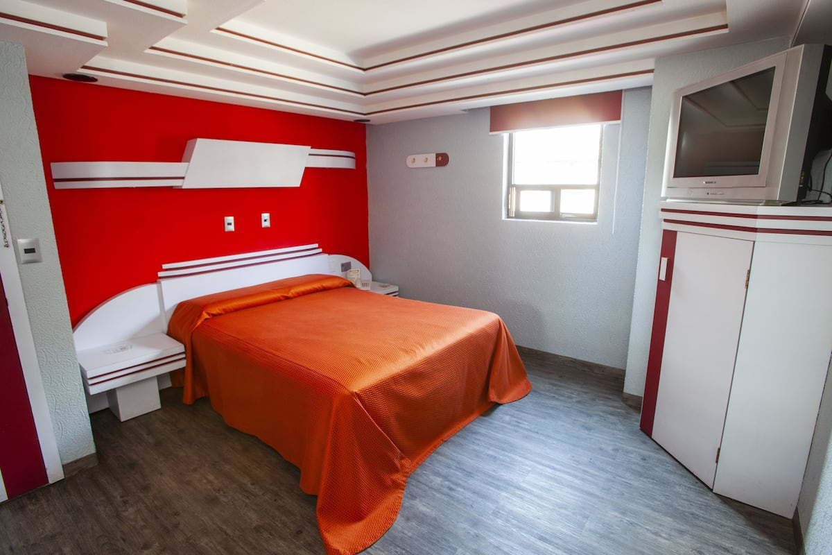 A compact room with a bed, a TV, and a wardrobe.
