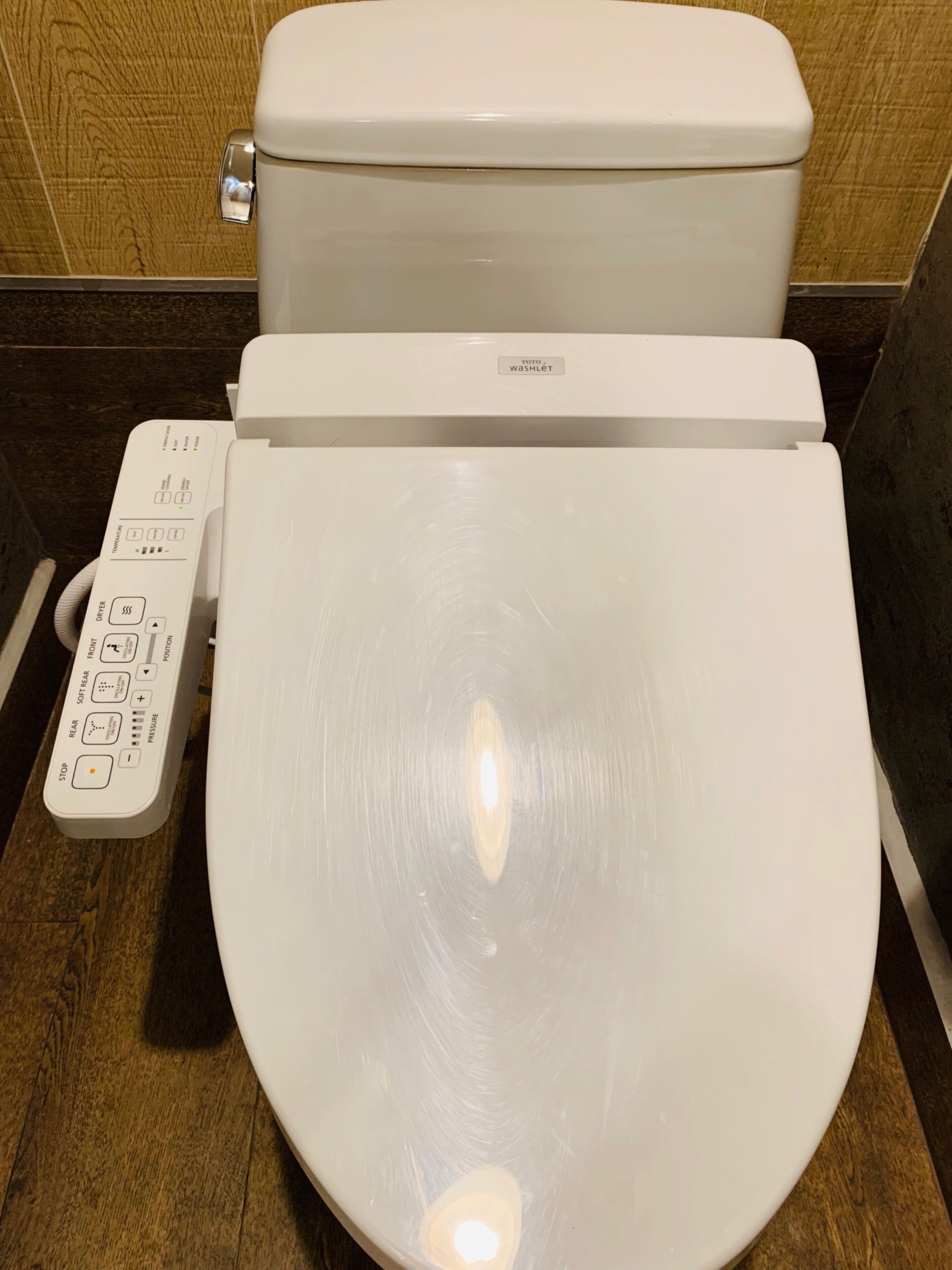 A modern toilet with a control panel featuring multiple buttons and a digital display.