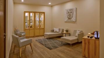 A modern living room with a sofa, armchairs, a coffee table, and a cabinet with glass doors.