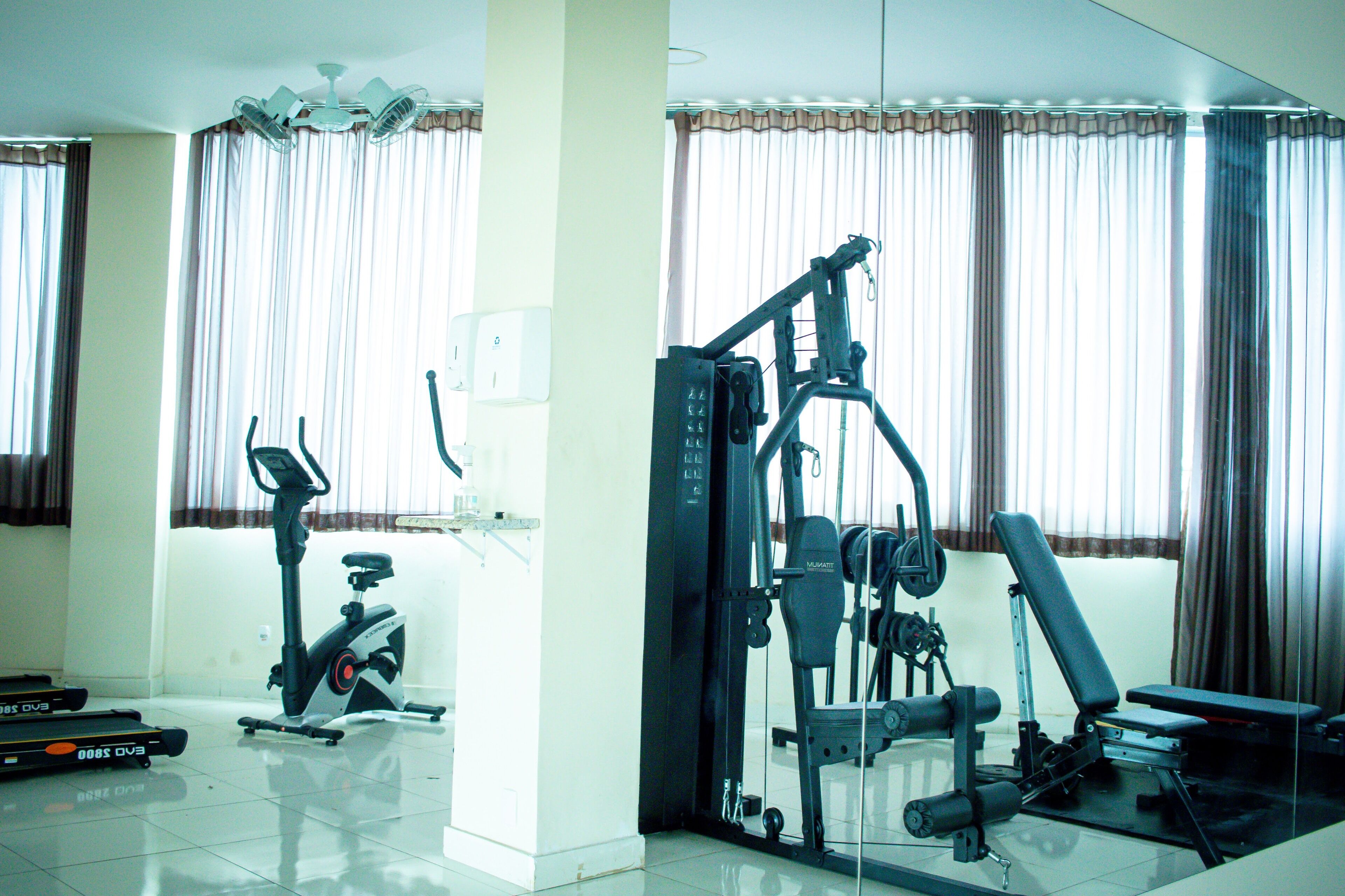 Een fitnessruimte thuis met een hometrainer, elliptische trainer en krachtapparaat.