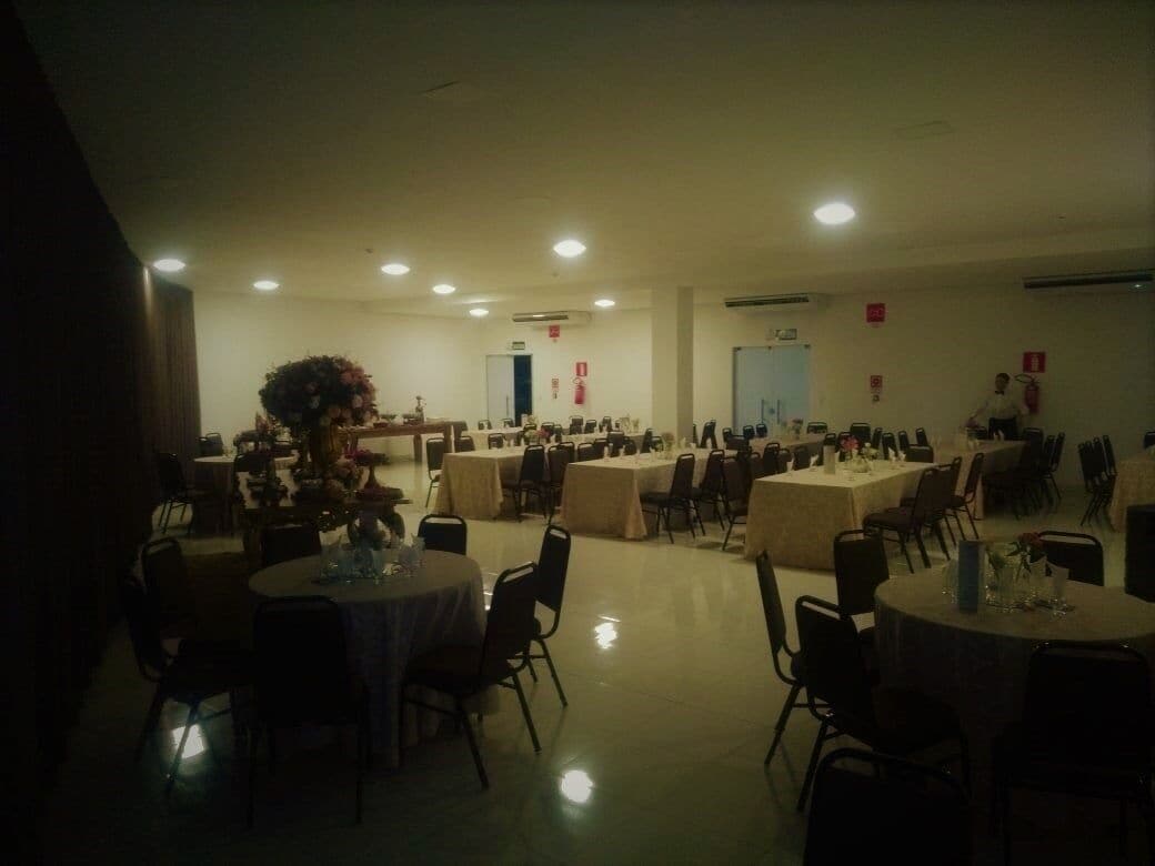 Un amplio salón de banquetes con varias mesas redondas y sillas, dispuestas en filas.