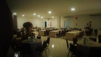 Un amplio salón de banquetes con varias mesas redondas y sillas, dispuestas en filas.