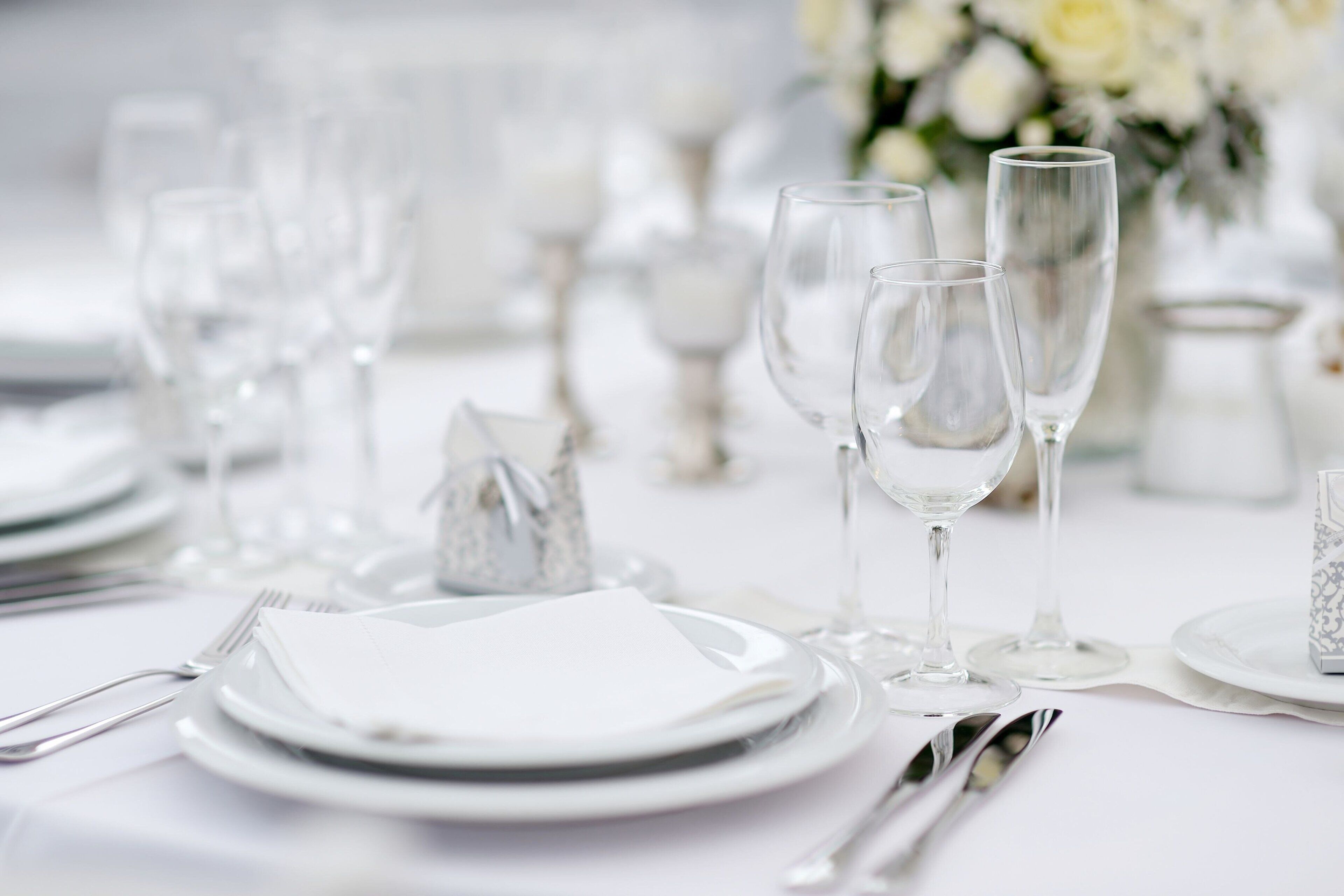 A table set for a formal event with white plates, clear glassware, and silverware.