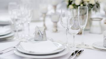 A table set for a formal event with white plates, clear glassware, and silverware.