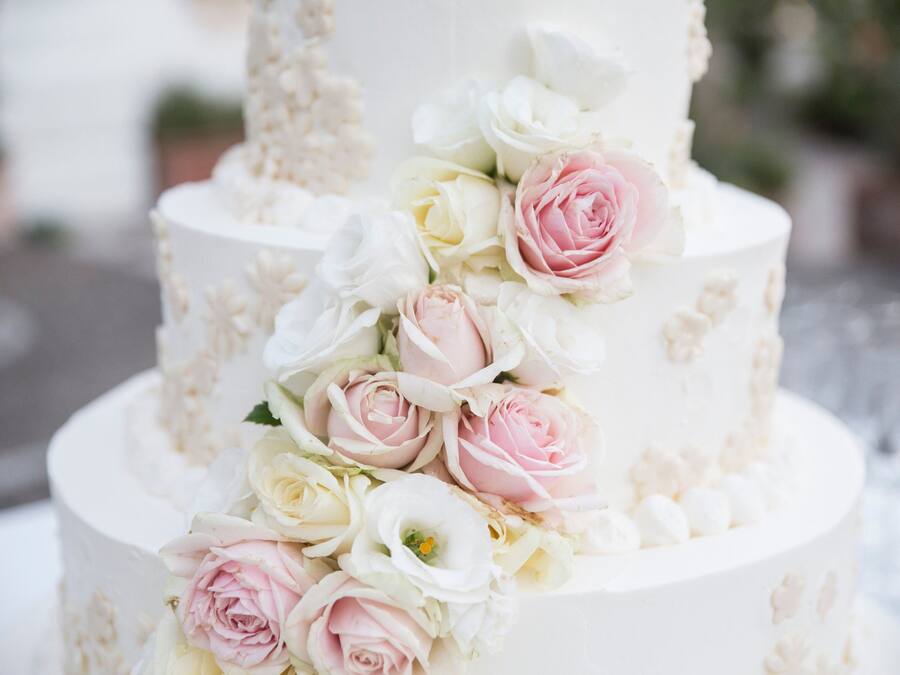 Un pastel de bodas de varios niveles decorado con rosas blancas y rosas.