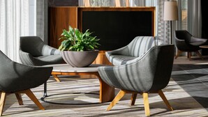 Una sala moderna con dos sillones grises, una mesa de centro de madera y una planta grande en maceta.