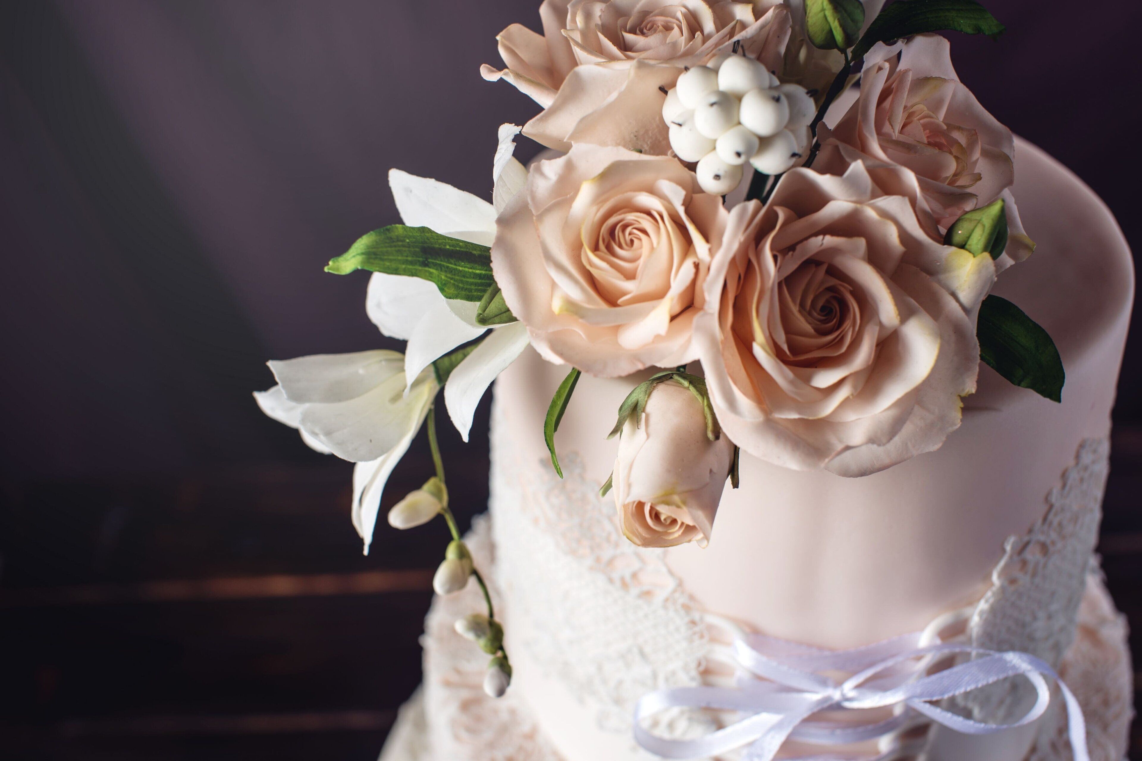 A wedding cake with roses and white flowers.