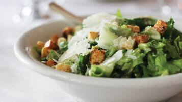 A bowl of Caesar salad with croutons and shaved Parmesan cheese.