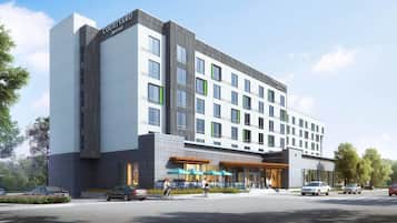 A modern hotel with a prominent Courtyard Marriott sign, multiple floors, and a ground-level restaurant with outdoor seating.