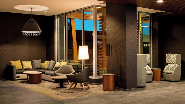 Un área de estar moderna con un sofá modular, sillones, una mesa de centro y una lámpara colgante.