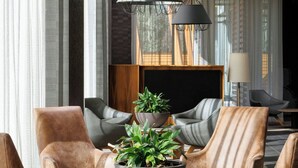 Una sala de estar moderna con sillones de cuero, una mesita de centro con una planta e iluminación colgante.