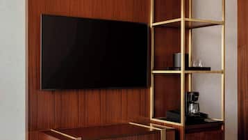 A hotel room with a wooden TV stand, a flat-screen TV, a coffee maker, and a bed.
