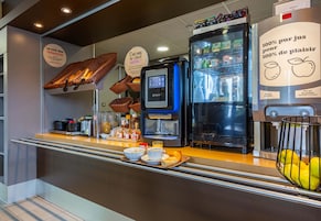 Una barra de desayuno con una máquina de café, refrigerador y cestas de pan.