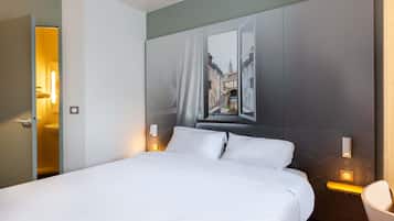 Una habitación de hotel con una cama, un cuadro de un paisaje urbano en la pared y vistas de la ciudad a través de la ventana.