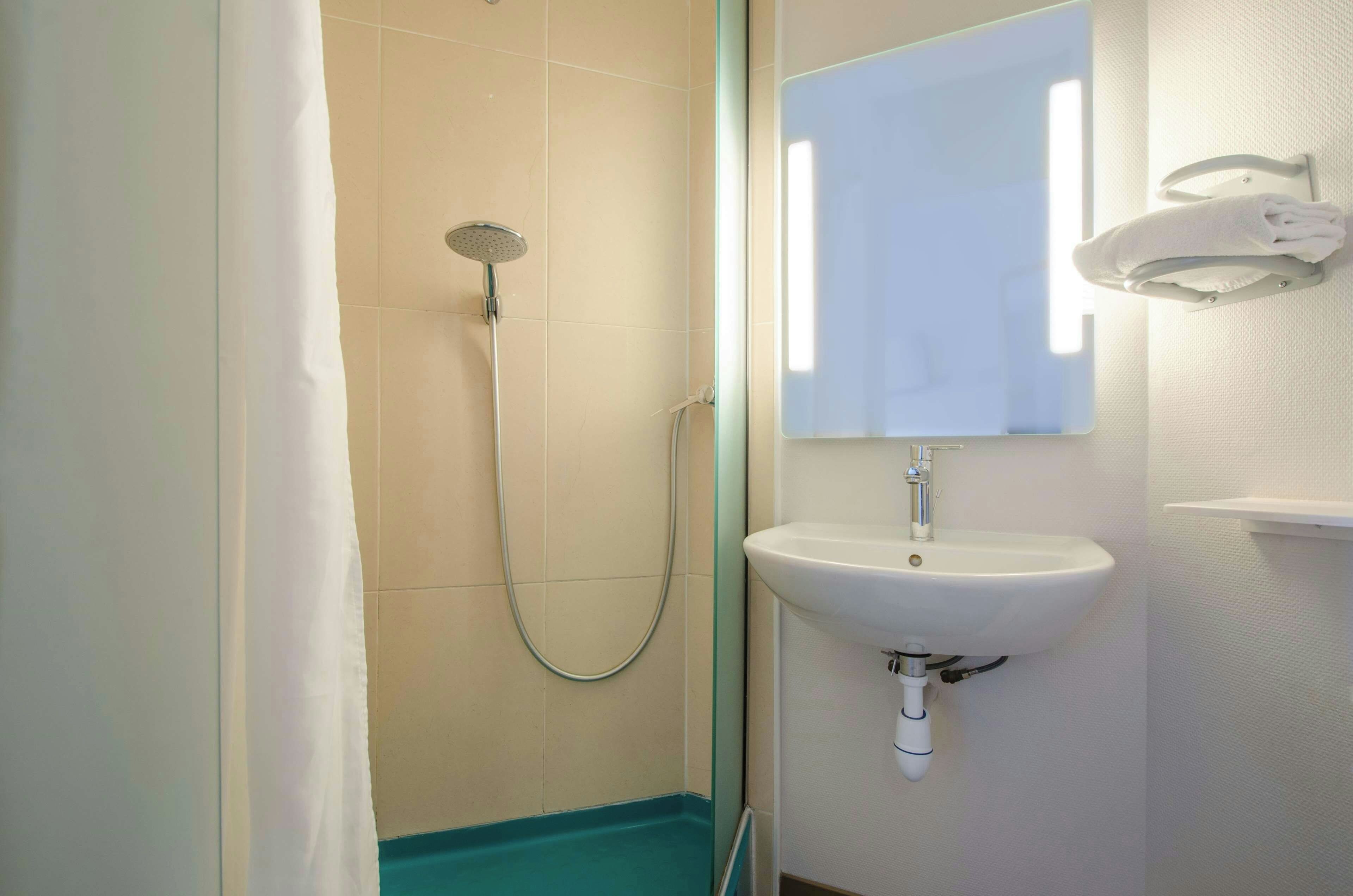 Une salle de bain avec une douche, un lavabo et un miroir.