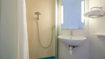 Une salle de bain avec une douche, un lavabo et un miroir.