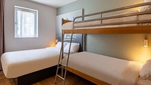 A room with two bunk beds, a window with curtains, and a bedside table with a lamp. - B&B Hotel Chartres 2 Le Coudray (Le Coudray)