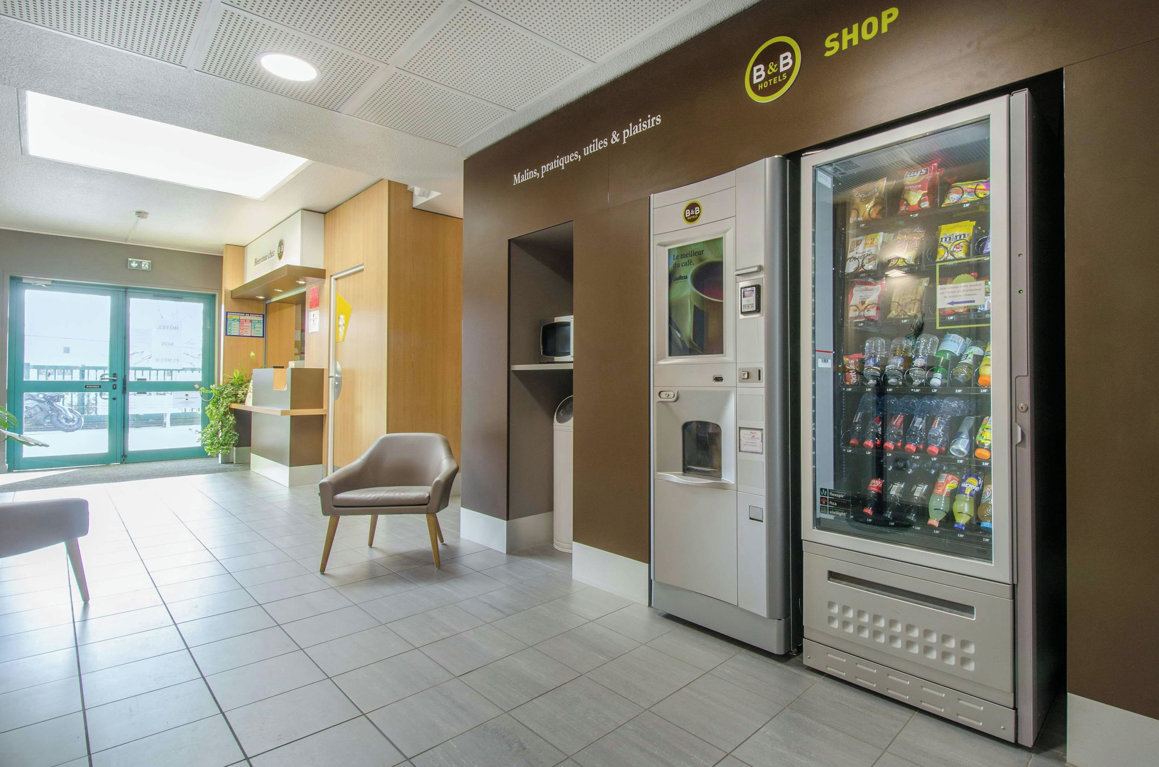 Um hall de hotel com área de estar, máquina de vendas automática e balcão de recepção.