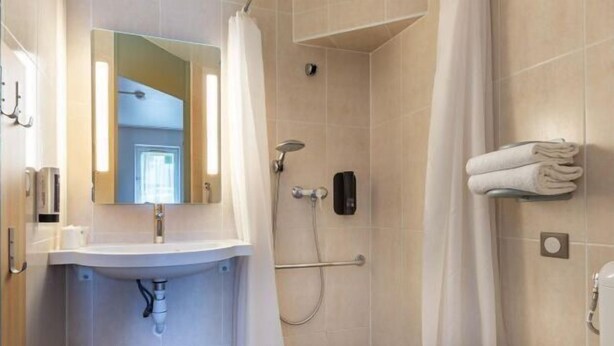 A bathroom with a sink, mirror, shower, and towel rack. - B&B Hotel Chartres 2 Le Coudray (Le Coudray)