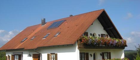 A traditional house with a sloped roof, multiple windows, and flower boxes.