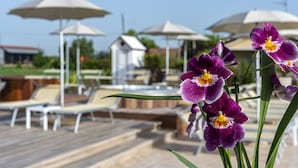 A poolside area with lounge chairs and umbrellas. - Agriturismo B&B Vista Parco (Ravenna)