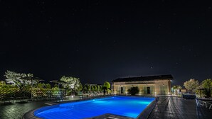 A swimming pool with a curved edge, surrounded by a brick deck and outdoor seating. - Agriturismo B&B Vista Parco (Ravenna)