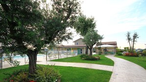 A landscaped garden with a curved pathway, a pool, and a building with a tiled roof. - Agriturismo B&B Vista Parco (Ravenna)