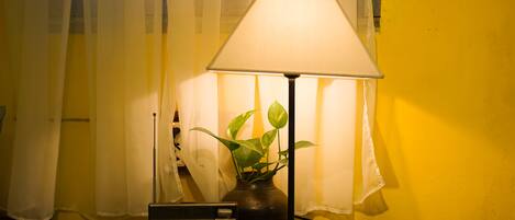 Una mesita de noche con una lámpara, un radio y un florero con una planta.