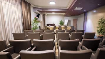 A conference room with multiple rows of chairs, a whiteboard, and a television on a stand.