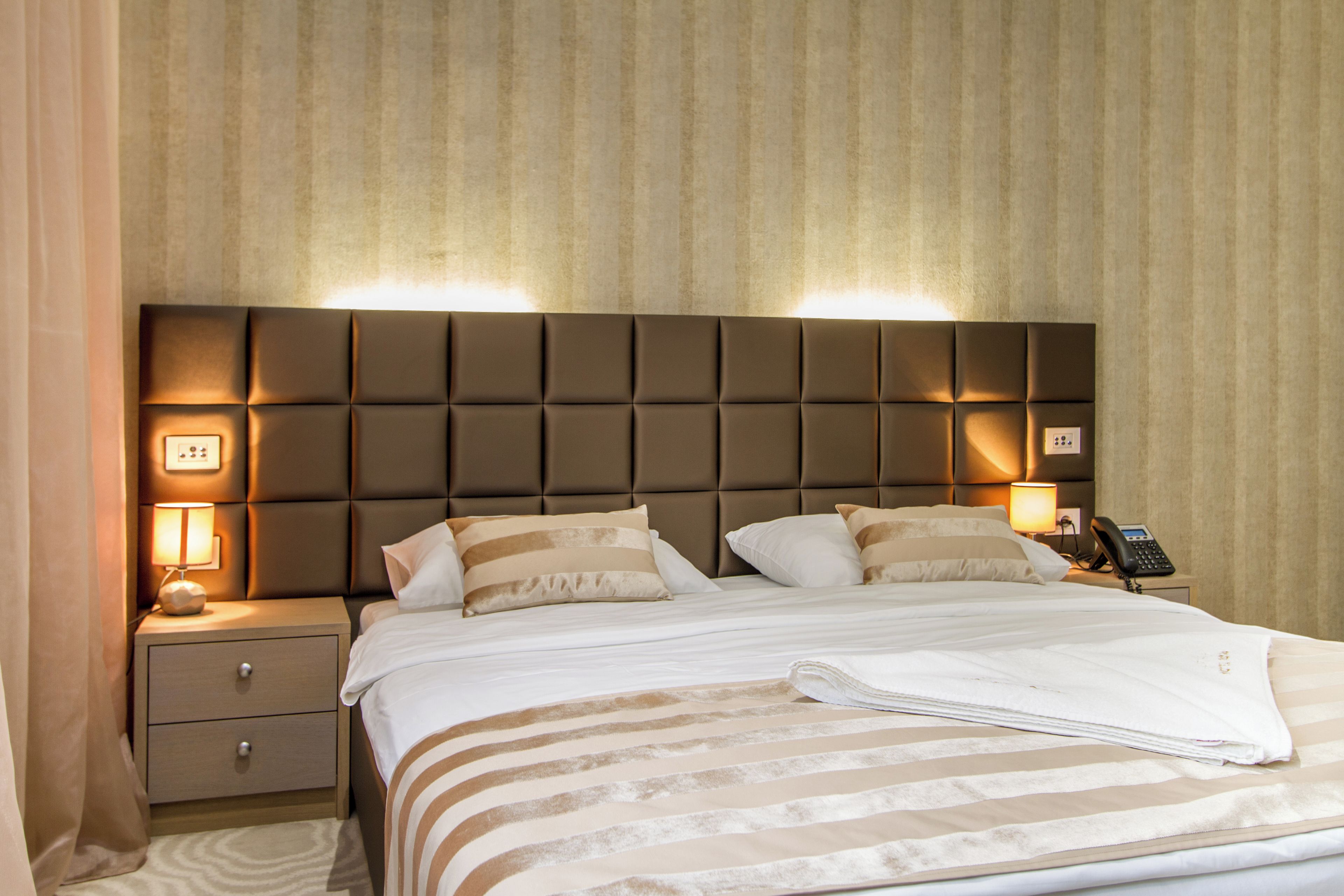 Una habitación de hotel con una cama grande, una mesita de noche con lámpara y un teléfono.