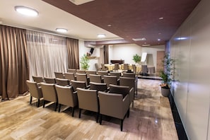 A conference room with rows of chairs, a piano, and potted plants. - Royal Airport (Velika Gorica)
