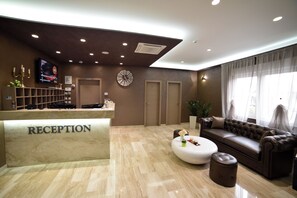 A reception area with a marble floor, a reception desk labeled 'RECEPTION,' a clock, a sofa, and a television screen.