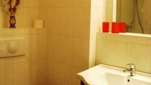 Et badeværelse med toilet, håndvask og bruser.