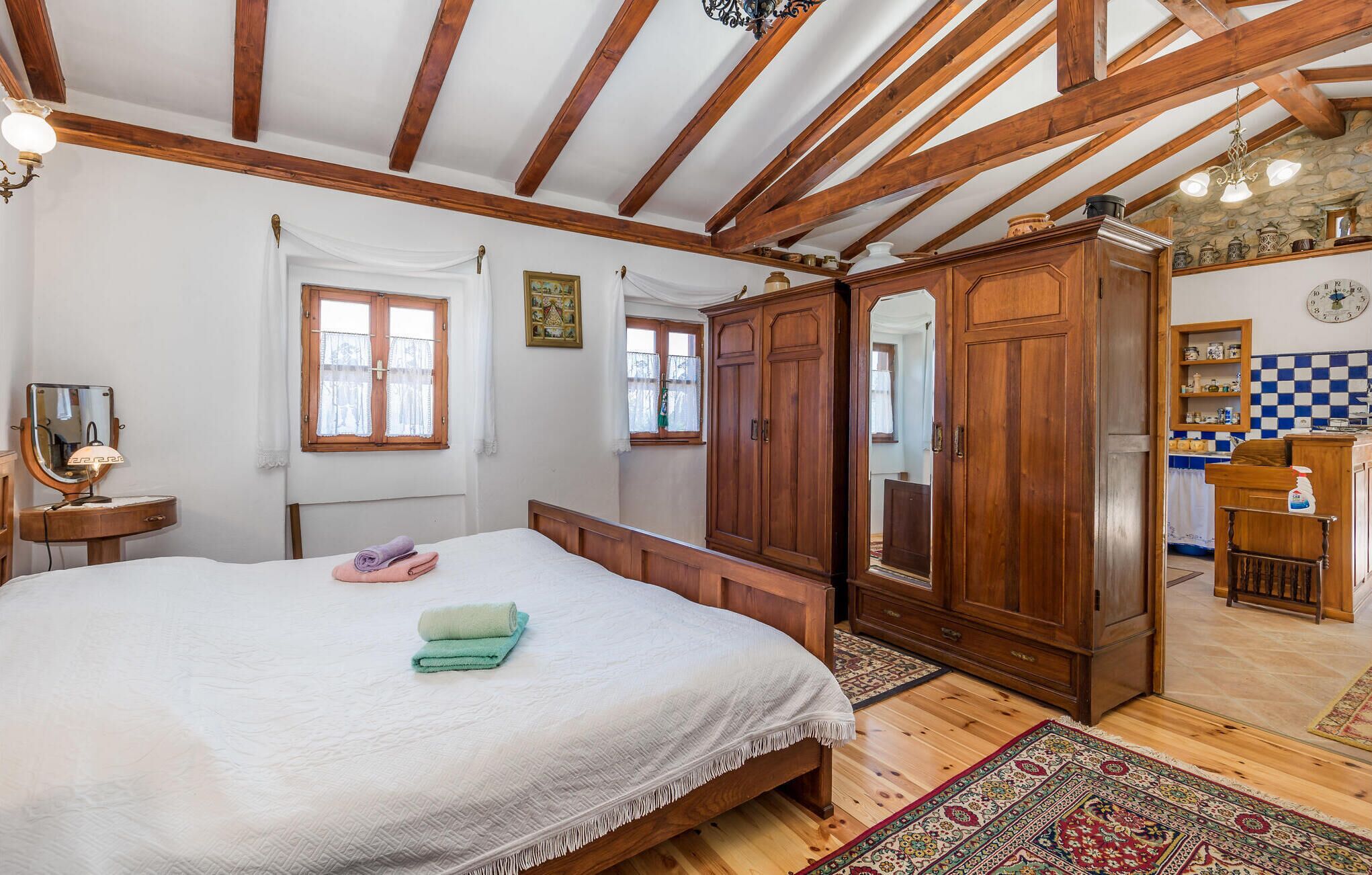 Un dormitorio con una cama grande, un armario de madera y una pequeña cocina con salpicadero a cuadros.