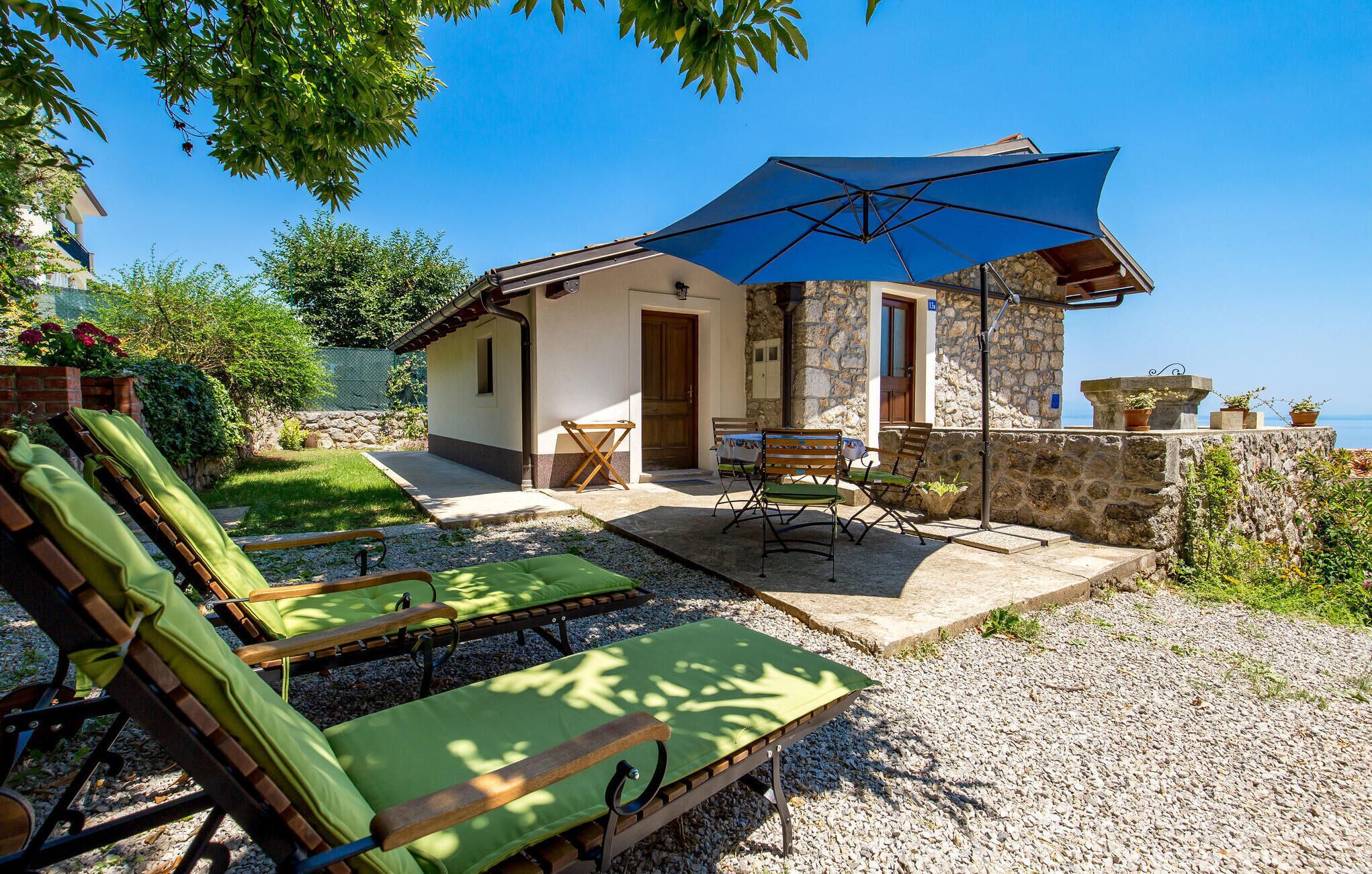 A villa with a patio, outdoor seating, and a stone wall.