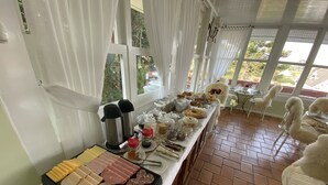 Buffet de l'esmorzar amb diversos plats i condiments, racó de cafè i zona de seients amb cadires i taules.