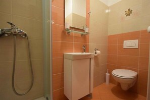 A bathroom with a shower, sink, toilet, and a mirror. - Studio with air conditioning (Malinska)
