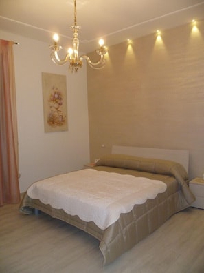 A bedroom with a bed, a chandelier, a painting, and a nightstand. - B&B Domus Pompeii (Pompei)